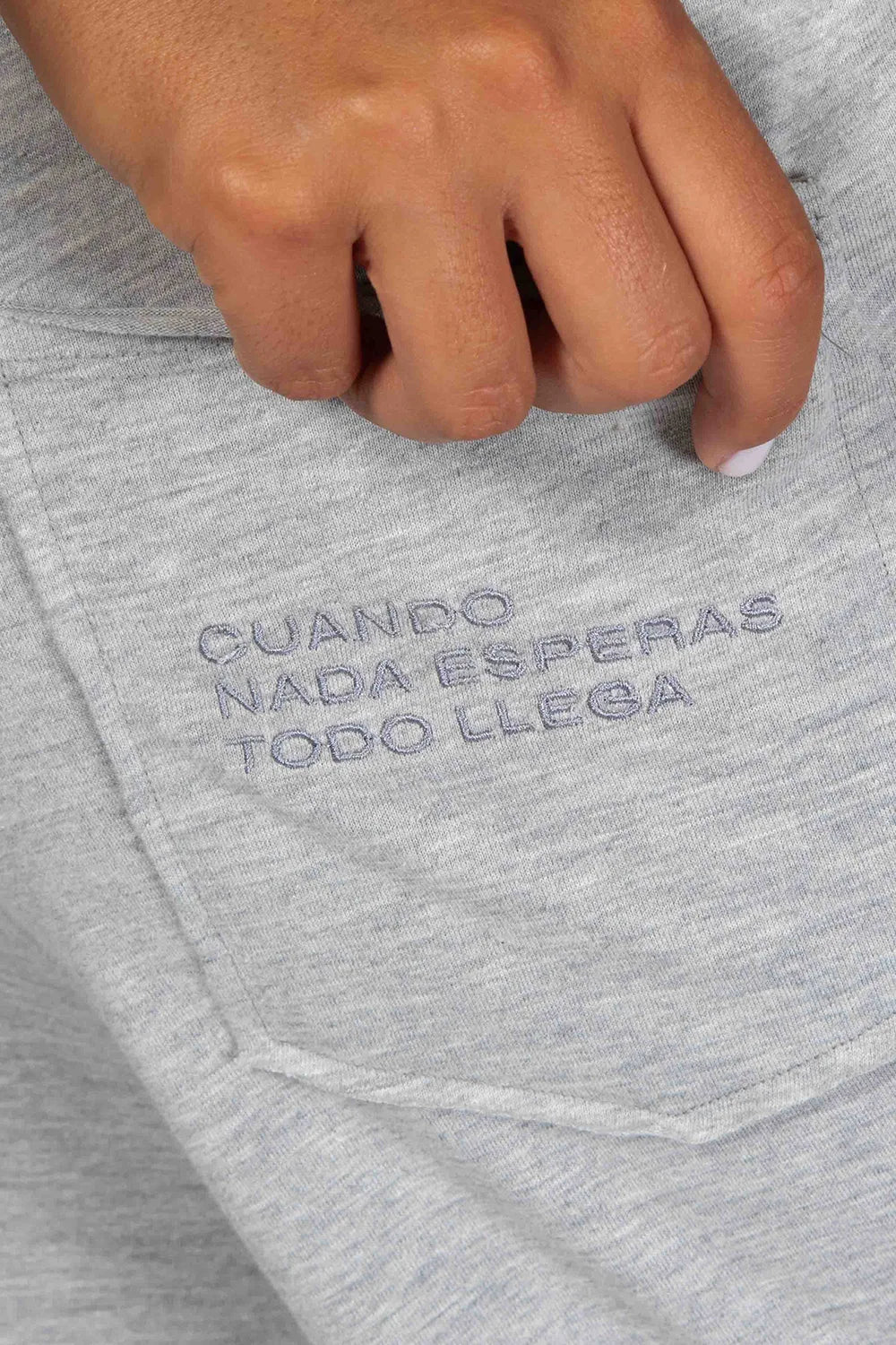 Detalle borado bolsillo trasero con frase "Cuando nada esperas todo llega". Peto Freedom color gris Quiet Gray de Yogimi. Esas prendas que una vez te las pones no te quieres quitar.
