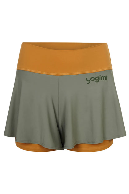 Silueta de pantalones cortos de yoga de Yogimi en color mostaza con capa verde. Modelo Prana Inca Gold-Green